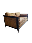 An elegant, two-seater Neoclassical-style settee featuring a dark wood frame and golden-orange botanical upholstery. The settee has a straight back with two rectangular cushions and two matching bolster pillows tucked against the scrolled, dark wood arms. The fabric is a rich tapestry weave with a large-scale, stylized leaf pattern in autumnal shades of gold, amber, and terracotta. The wooden frame is detailed with fluted stiles and tapered, turned legs.