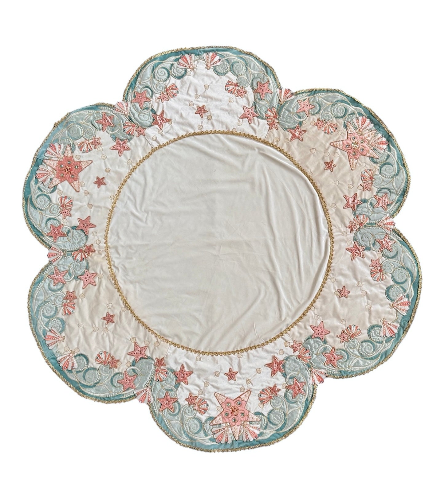 A round, cream-colored tablecloth featuring a dramatic, scalloped border shaped like six large flower petals. The border is intricately embroidered with a coastal motif including pink starfish, seashells, and teal-blue swirling waves. Gold beaded accents line the inner circular seam and the outer edges.
A long, narrow cream runner with matching scalloped, wavy edges. It is adorned with the same nautical embroidery of pink starfish and seashells scattered across the center and concentrated along the edge.