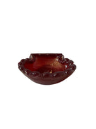 A handcrafted Murano glass bowl with a ruffled edge, deep red color, and gold specks created using the "oro zecchino" technique. The surface has a crackled gold pattern that reflects light, making it a striking decorative piece.
