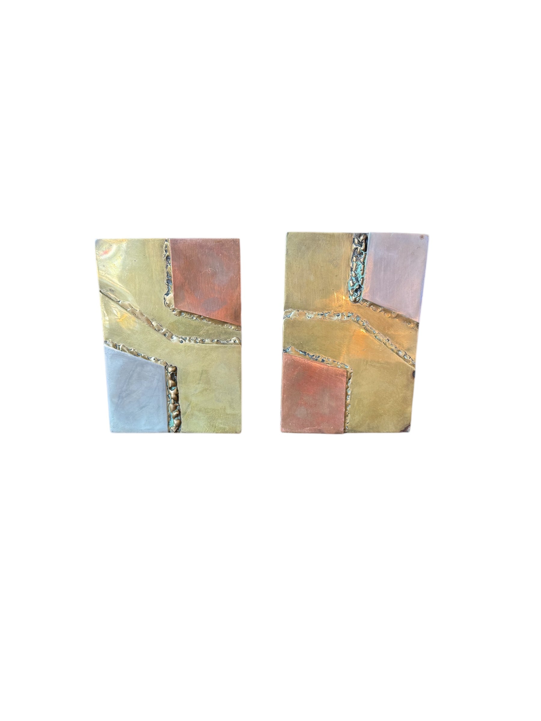 Close-up of two David Marshall Brutalist bookends. The bookends feature contrasting silver and bronze metal panels, separated by raised textured bronze seams. The bookends have a rough, geometric design.