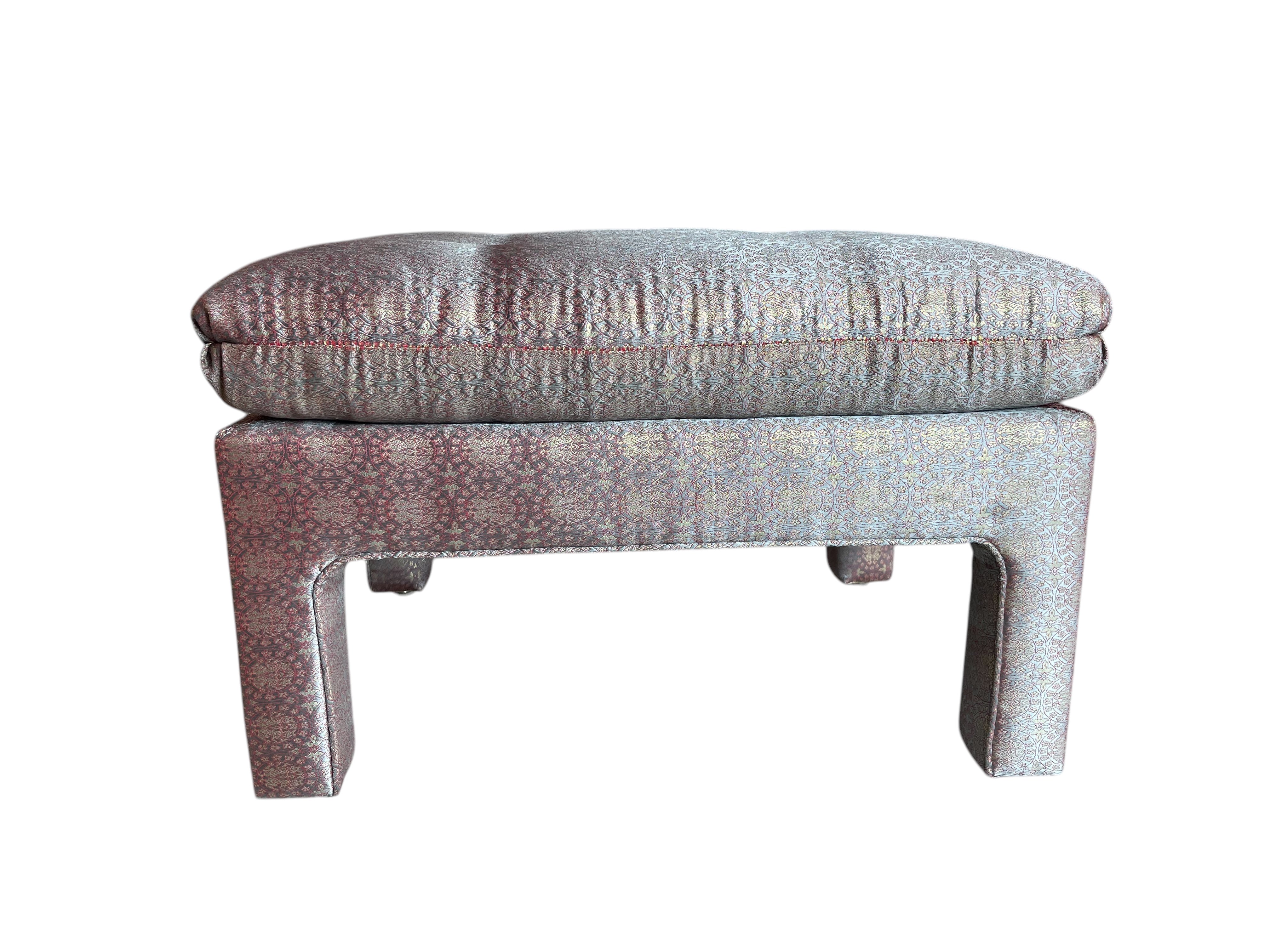 A vintage pink parson ottoman with a floral pattern on the cushion and a wooden frame.