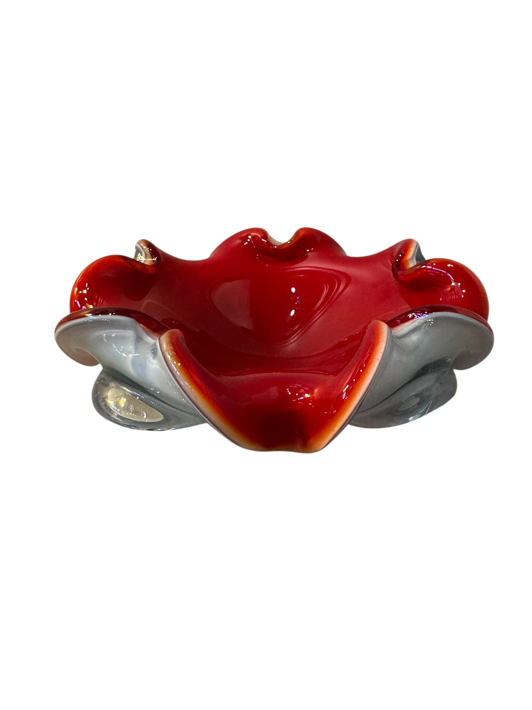 A Murano art glass bowl featuring a vibrant red interior encased in white glass, with a decorative ruffled edge. The piece is handblown, showcasing the Incamiciato technique.