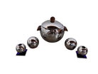 A set of vintage chrome-plated holloware featuring a central covered server with a relief penguin band and wood handles, flanked by two pairs of spherical shakers and candle holders on blue glass bases.
