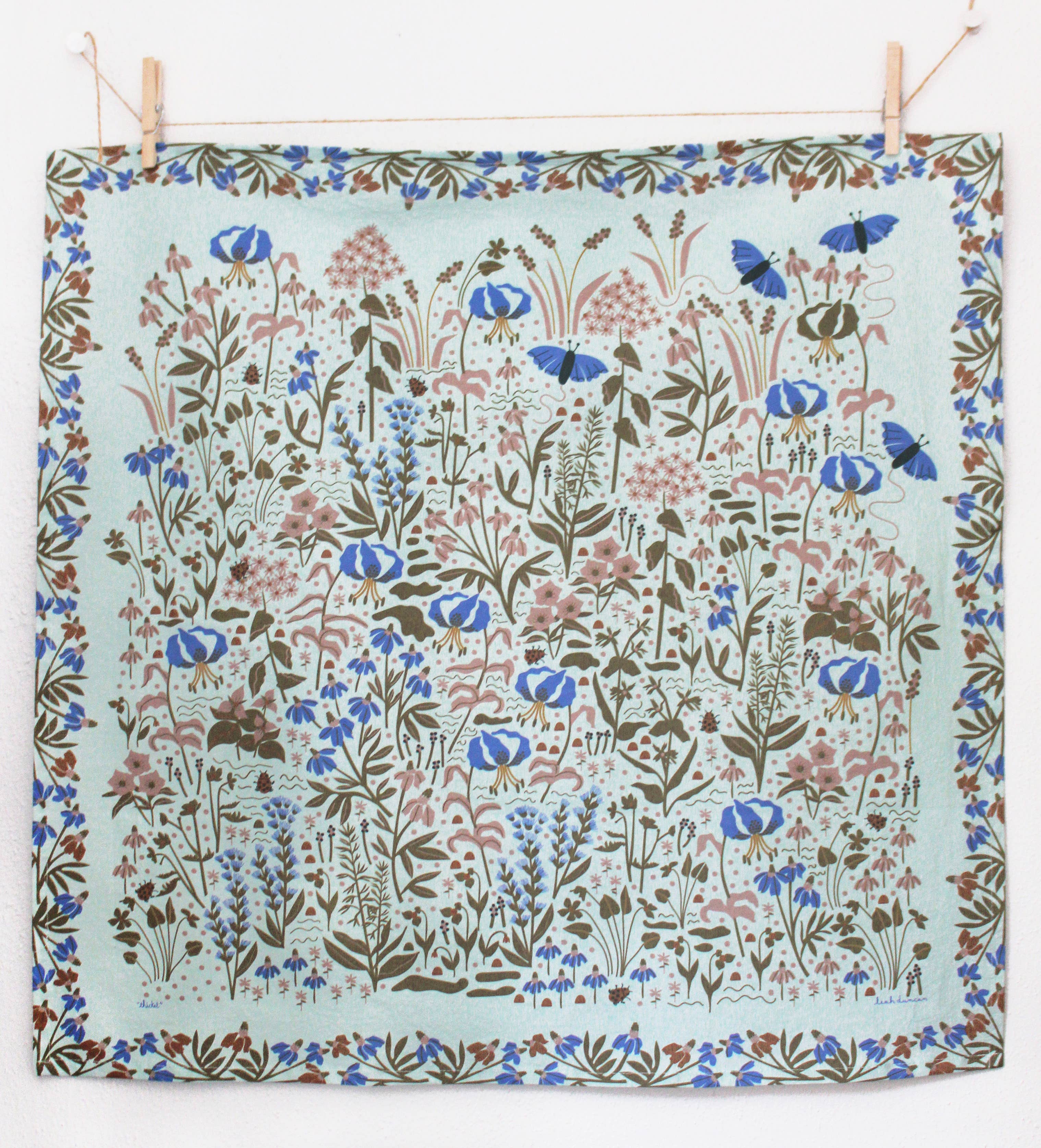 Floral patterned fabric hanging on a line with wooden pegs.