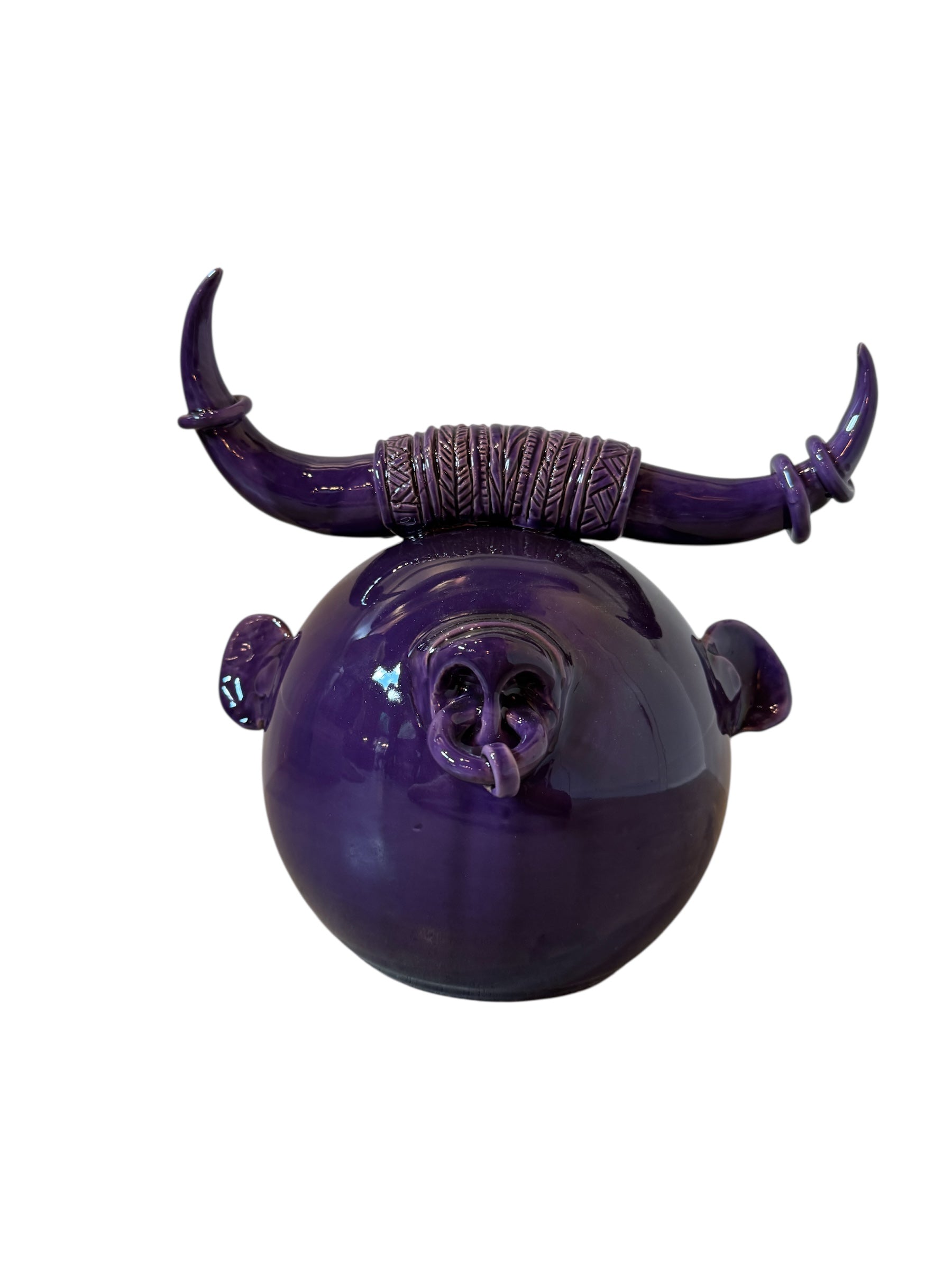 Glossy purple ceramic sculpture featuring a round body and stylized bull horns adorned with rings, and a nose ring. The sculpture has no eyes, but suggests a smiling expression.

"Toro Viola Sorridente" The Smiling Purple Bull by Enza Fasano Ceramiche
