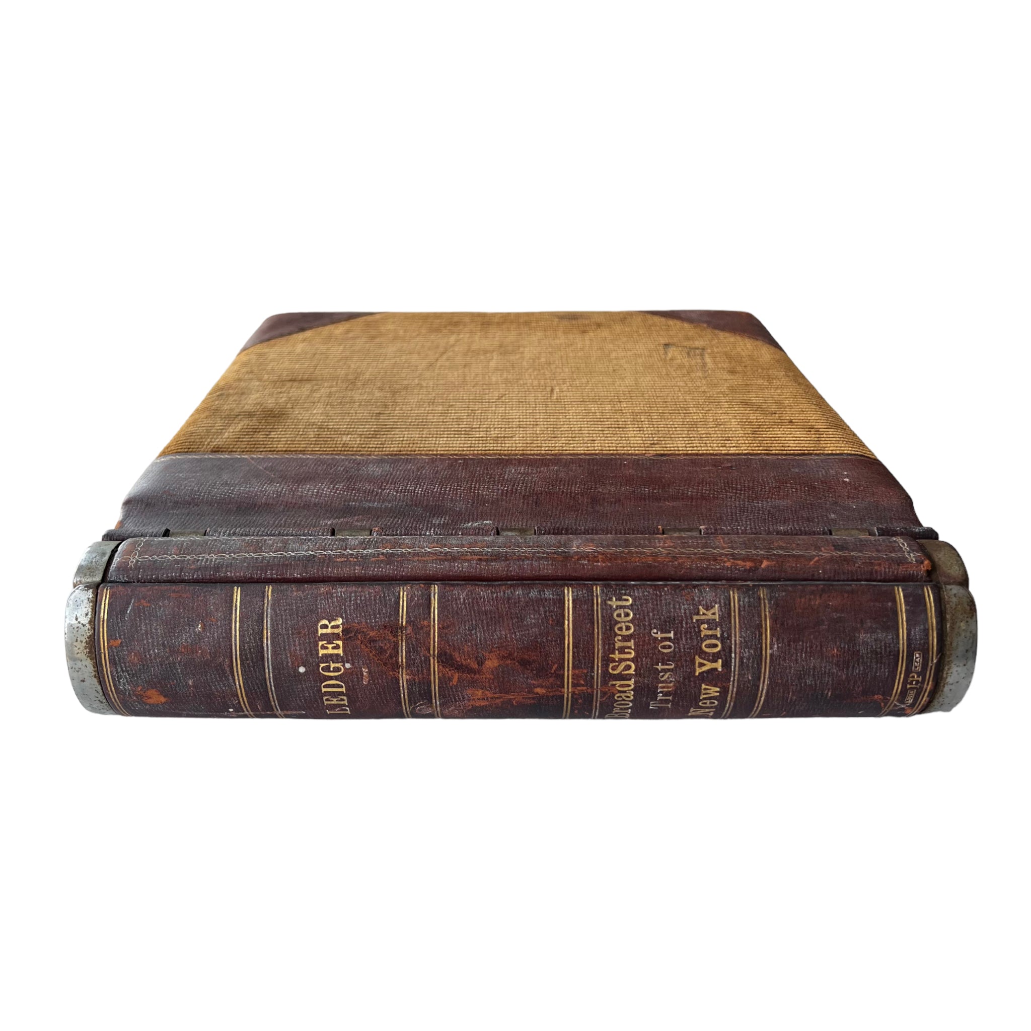 A vintage leather ledger book with metal hinges and spine, featuring text on the cover.